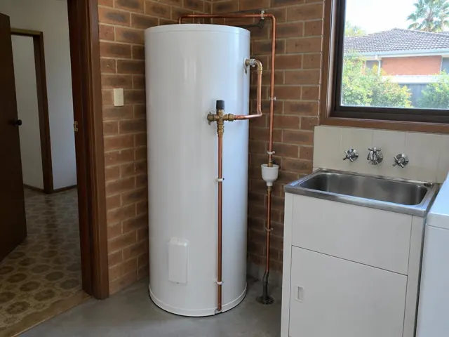 White hot water tank beside a laundry sink against brick walls in Cromer